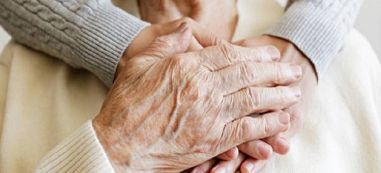 Mature female in elderly care facility gets help from hospital personnel nurse. Senior woman, aged wrinkled skin &amp; hands of her care giver. Grand mother everyday life. Background, copy space, close up