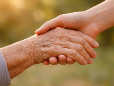 Elderly hand reaching out to a young hand under the sunlight